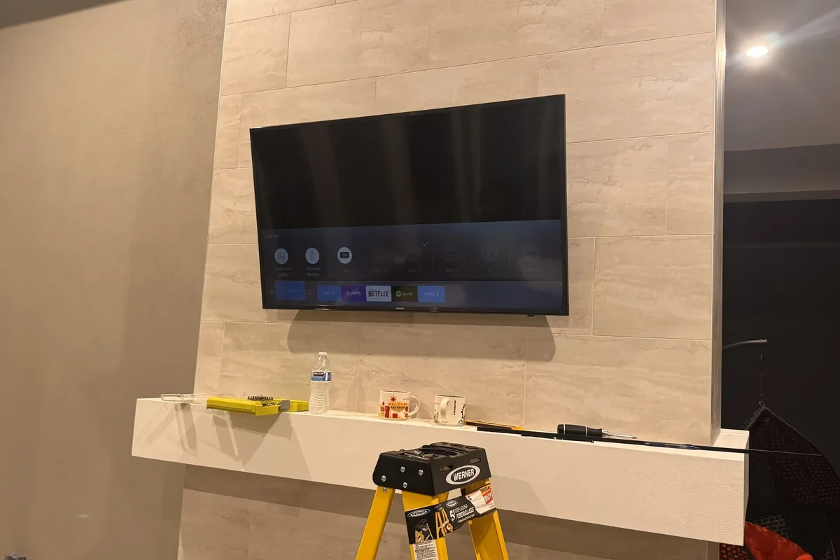 Wall-mounted flat-screen TV above a white mantle in Naples home
